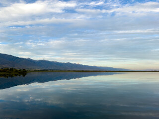 A quiet mountain lake Issyk-Kul, surrounded by green valleys and majestic mountains. The perfect spot for tourism and peaceful relaxation in Kyrgyzstan.