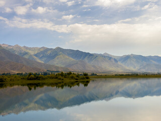A quiet mountain lake Issyk-Kul, surrounded by green valleys and majestic mountains. The perfect spot for tourism and peaceful relaxation in Kyrgyzstan.