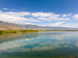 Obraz premium A quiet mountain lake Issyk-Kul, surrounded by green valleys and majestic mountains. The perfect spot for tourism and peaceful relaxation in Kyrgyzstan.