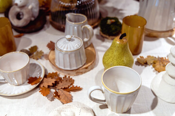 Autumn table setting with white cups and yellow oak leaves on the table