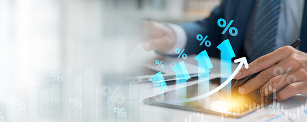 A businessman studies a digital chart with upward arrows and percentage symbols, representing financial growth, progress, and investment returns.