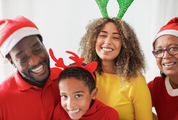 Portrait of multi generational african family celebrating christmas day together at home and smiling on camera - Grandmother, young couple and son - Soft focus on young woman face