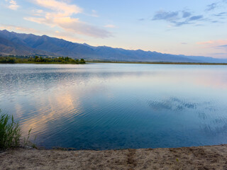 A wooden staircase leading into the clear waters of Issyk-Kul lake, with visible underwater vegetation. A perfect spot for water relaxation and enjoying nature