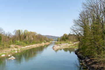 Beautiful rural landscape with river in a limestone bed, reflecting the trees on both sides, under...