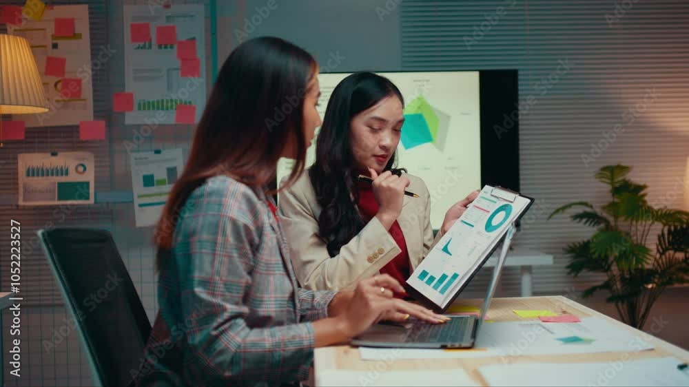 Poster two businesswomen are working late in the office, collaborating on a project. they are reviewing fin