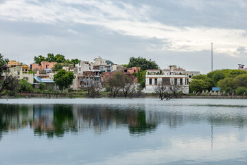 Obraz premium Serene Lake with city View and water Reflections Under Bright Sky at morning