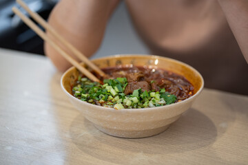 Close up yummy chinese lanzhou beef noodles and meat in brown bowl at noodle restaurant.