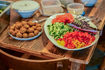 Leckere Falafel-Bällchen und Salat auf einem Teller steht zur Zubereitung von Falafel auf einem Holztisch in der Küche