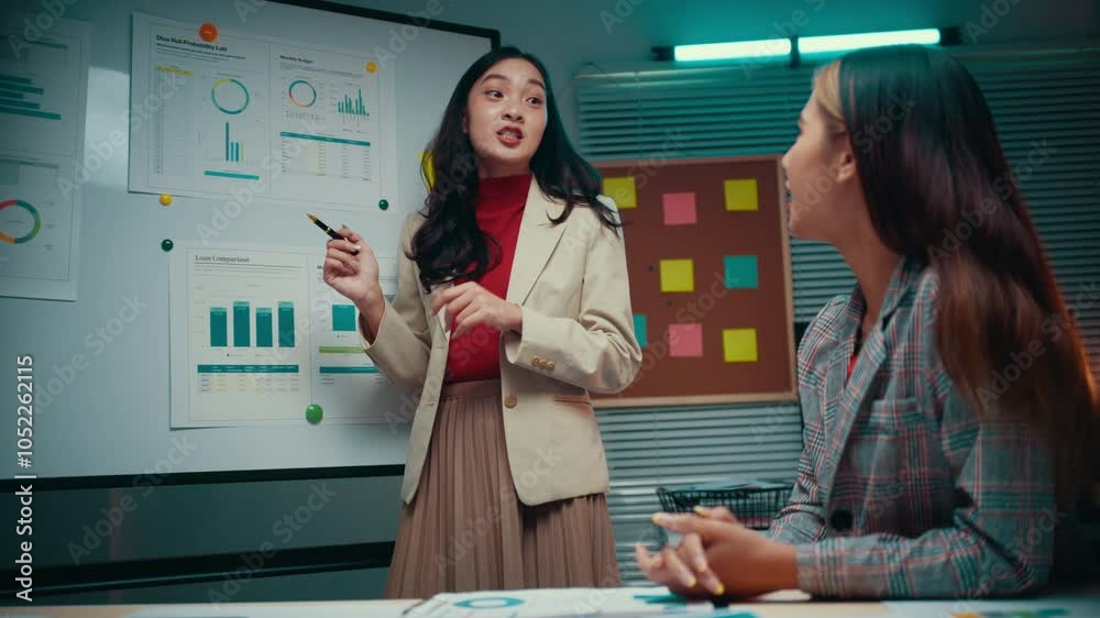 Aufkleber Businesswoman presenting a business plan engages in a discussion with her colleague, analyzing data and figures displayed on a whiteboard in a professional office setting