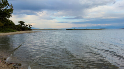 The calm waters of Issyk-Kul lake reflect dramatic clouds and mountains. Silence and tranquility in a natural oasis in Kyrgyzstan