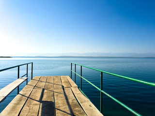 A wooden pier on Issyk-Kul lake with a view of the mountains. A beautiful spot for relaxation and...