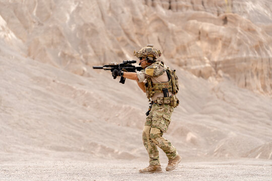 Side view of military or soldier with hold gun and point forward also walk in battlefield near the mountain during outdoor practice.