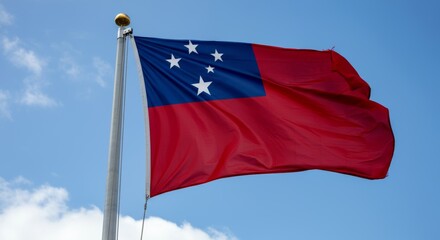 Samoan national flag waving on a flagpole against blue sky.