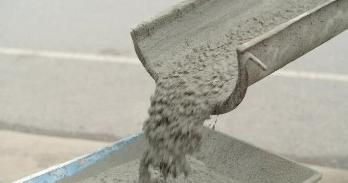 Cement from the cement mixer truck is poured into the Wheelbarrow.Close up Ready-mixed cement flows down from the cement truck.