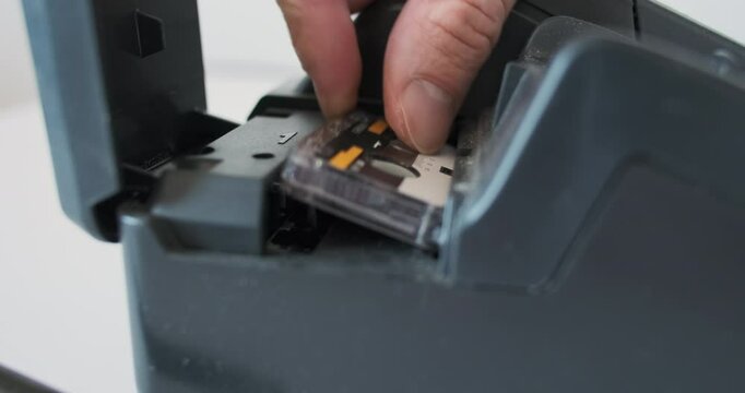 Micro cassette insert into an old telephone answering machine, fax, analog recording of a conversation, retro device, side-view close-up