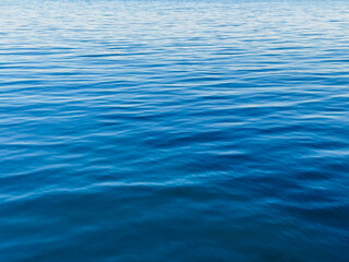Texture of blue calm water creates a serene and peaceful background. The natural beauty of water reflects the essence of nature, evoking a sense of tranquility reminiscent of the sea.