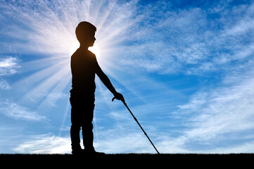 A silhouette of a blind boy with a cane, illuminated by the sun's rays