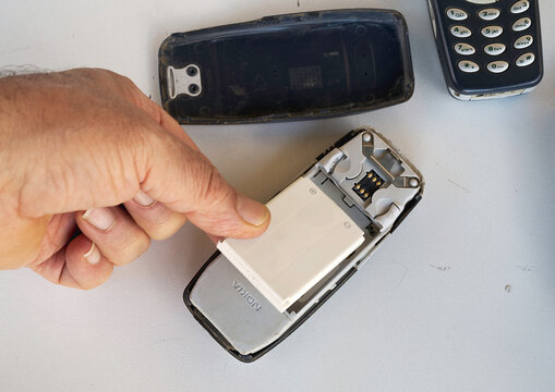 Modugno, Italy - September 20, 2024: The back cover is removed from an old Samsung smartphone to remove the lithium battery because it is exhausted. Obsolete and dirty smartphone, worn out, scratched 