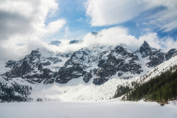tranquil view of Morskie Oko in Tatra National Park, Poland, showcasing majestic snow-covered mountains, serene frozen lake, and reflections on a chilly winter day. Winter landscape © ver0nicka