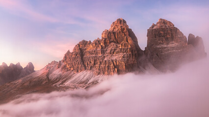 Sunrise or sunset over Tre Cime in the Italian Dolomites with a colourful sky and cloud inversion,...