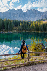 A hiker admires the stunning reflections of mountains in the tranquil waters of the Dolomites