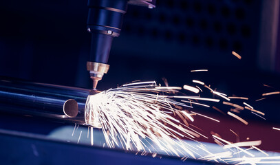 Closeup CNC gas cutting metal sheet, sparks fly. Blue steel color, modern industrial technology.