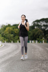 Runner's High: A determined woman in athletic wear jogs down an empty road, her towel draped over her shoulder, her face radiating focus and energy.  The image embodies the spirit of fitness.