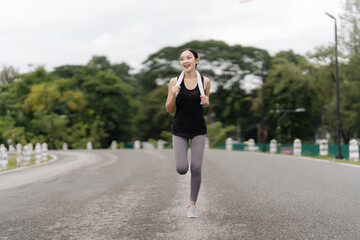 Determined Runner: A young woman in workout attire runs confidently along a paved road, radiating...