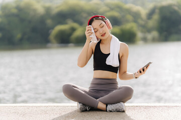 Post-Workout Serenity: Young woman in sportswear rests after exercise, enjoying music with...