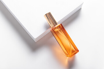 Small orange glass perfume bottle with golden cap on white background. Perfume samples