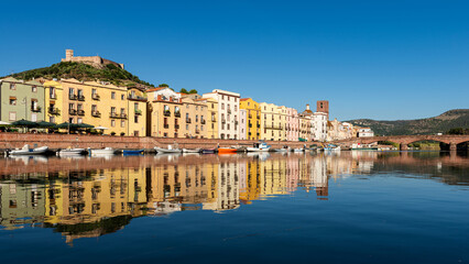 Fototapeta premium Spectacular view of the picturesque town of Bosa with its colorful houses reflected in the Temo River at golden hour. Sardinia, Italy.