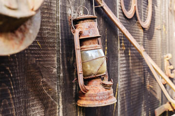 Antique kerosene lamp with rustic metal and glass structure. Old-fashioned lantern flea market. Evoking historical charm. Isolated aged lamp on wooden wall. Ideal for rustic, retro decor.