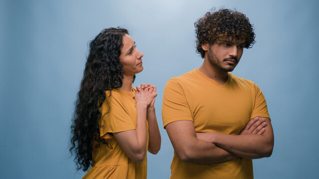 Offended Arabian man Indian husband boyfriend ignoring Latino Hispanic woman wife girlfriend asking forgiveness apologizing after quarrel conflict guilty saying sorry apology at studio blue background
