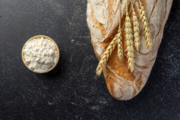 A rustic loaf of bread with unique textures sits alongside wheat stalks, placed creatively on a...