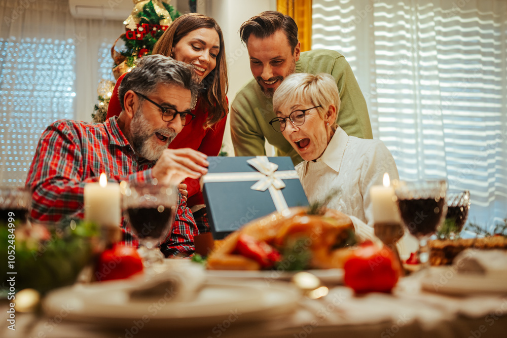 Wall mural Family having christmas dinner together opening present