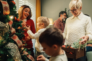 Happy family decorating christmas tree with ornaments at home