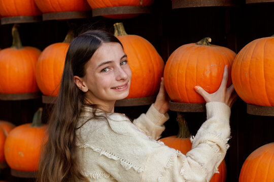 beautiful girl beaming while grabbing a pumpkin