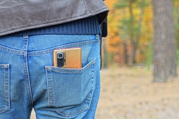 one modern orange glass camera and display electronic portable mobile phone in man's back pocket of...