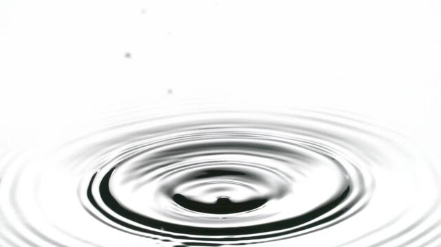 A single drop of water falling into a pool of water in slow motion.