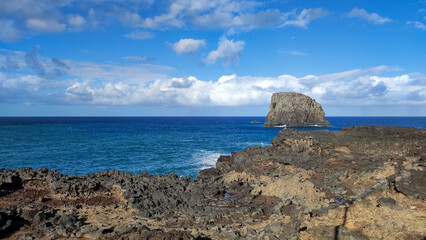 Rocky shore and ocean with prominent rock formations under a blue sky. Madeira, Portugal, Cais do Porto da Cruz
