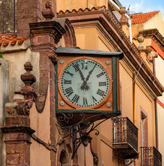 An old historic wall clock on the facade of a church in the old town centre of Bosa, Sardinia