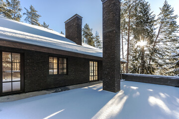 A tranquil terrace blanketed in snow offers an amazing view of tall trees reflecting sunlight. The winter landscape creates a peaceful atmosphere outdoors.