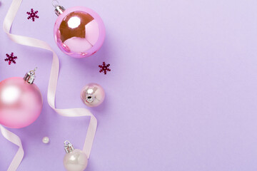 Pink christmas balls with decor on color background, top view
