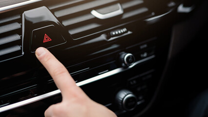 Obraz premium Warning Concept. Man pushing red triangle car hazard lights button in his luxury auto, being towed