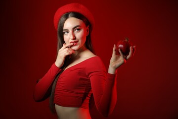 Woman with ripe pomegranate on red background