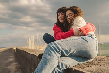 Diverse friends hugging outdoors at sunset, authentic friendship moment with Generation Z women