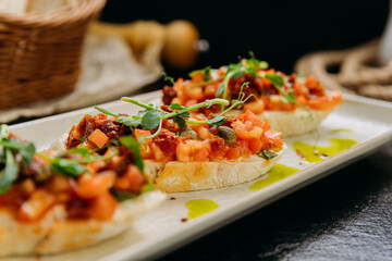 Rustic bruschetta topped with fresh tomatoes, sun-dried tomatoes, herbs and olive oil drizzle