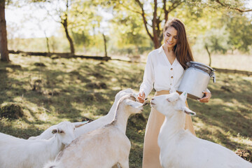 Woman Feeding Goats on a Sunny Pasture, Embracing Rural Life and Nature with a Joyful Expression