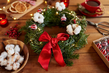 winter holidays, diy and hobby concept - close up of christmas fir wreath and decorations on wooden table