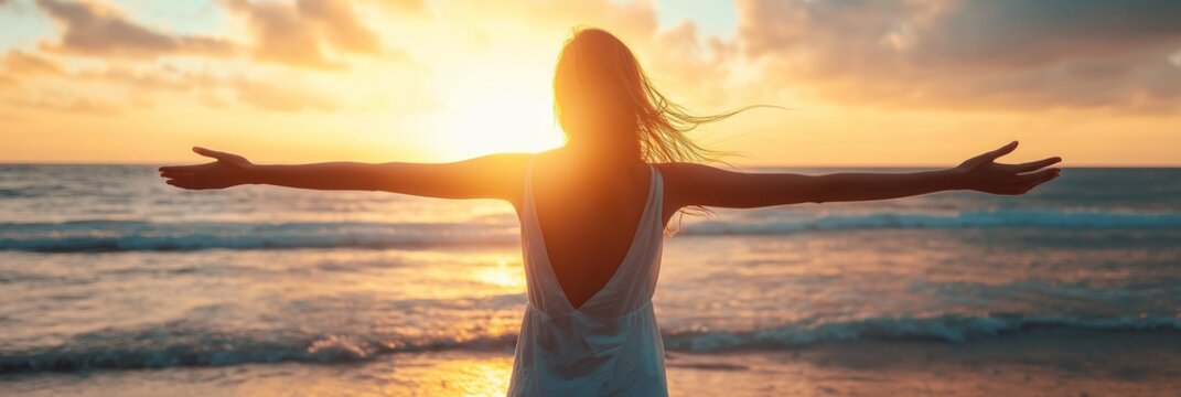 A woman stands on the beach, arms wide open, embracing the warmth and beauty of a breathtaking sunset.